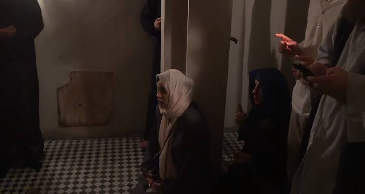 Schemering scène van vrouwen zittend op betegelde vloer met patronen in een donkere Marokkaanse kamer.