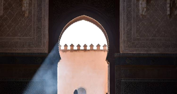 Rayon de soleil traversant une arche marocaine ornée avec des carreaux complexes et du travail de plâtre