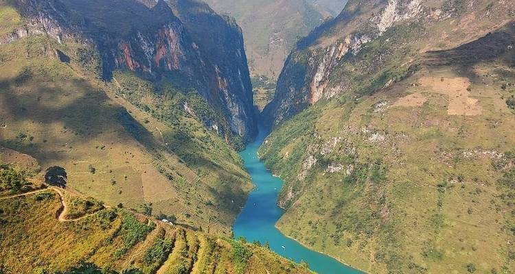 Dramatische Vogelperspektive eines türkisfarbenen Flusses, der sich durch steile Kalksteinklippen und terrassierte Hügel schneidet.