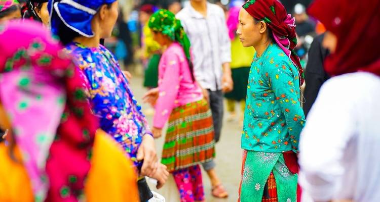 Farbenfroh gekleidete Hmong-Frauen mischen sich auf einem lebhaften Freiluftmarkt in Nordvietnam unter die Leute.