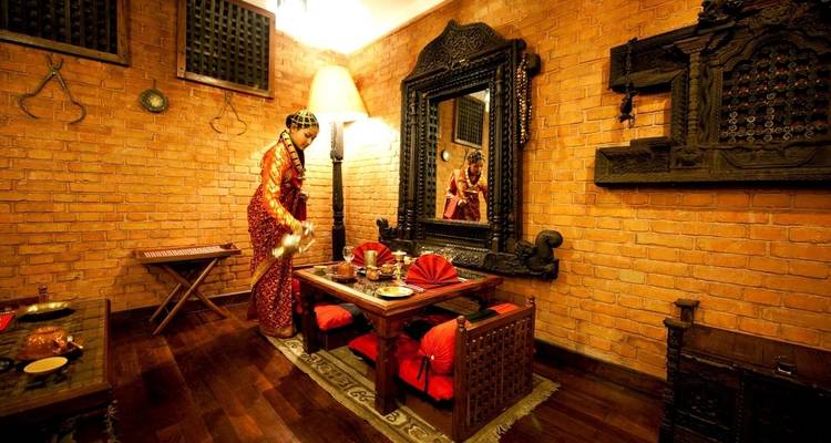 Dining setup in a traditional room with a person serving water.