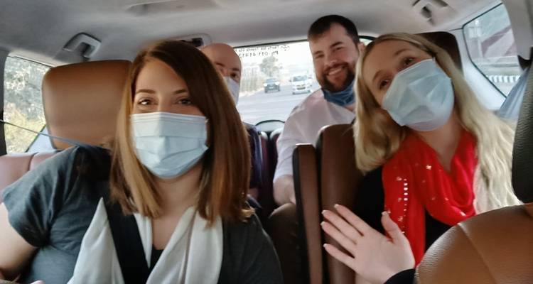 Toeristen in een voertuig met mondkapjes op