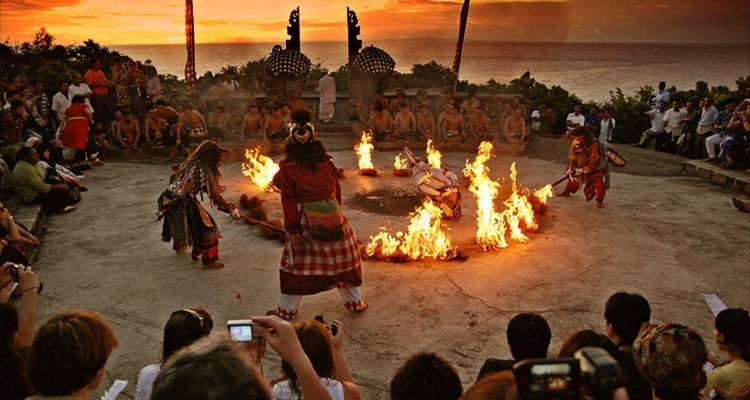 Espectáculo de danza cultural con fuego, bajo un cielo de atardecer.