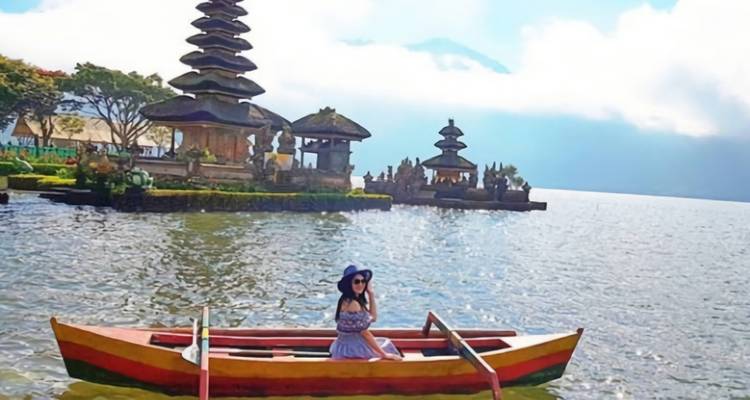 Mujer en una barca en un lago con un templo de fondo.