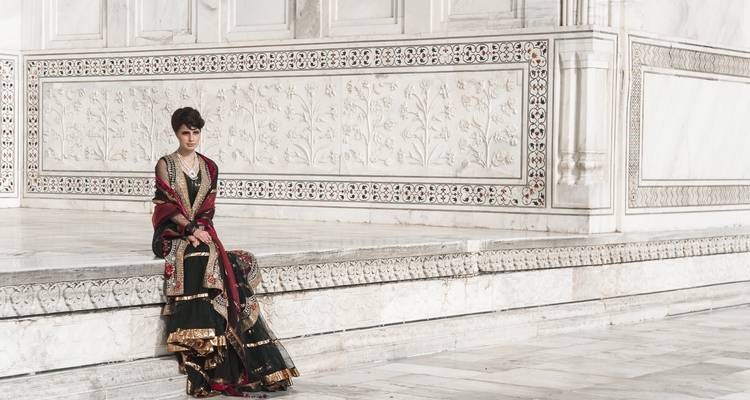 Personne en tenue traditionnelle assise sur le marbre blanc du Taj Mahal.