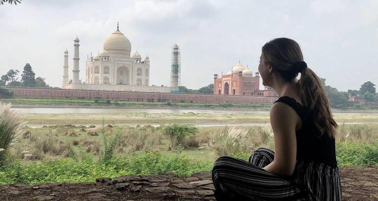 Personne assise près du Taj Mahal avec la structure emblématique en arrière-plan.