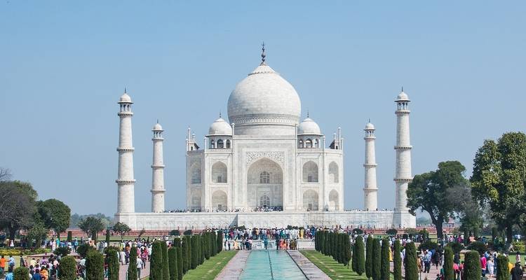 De Taj Mahal met mensen die op de voorgrond lopen.