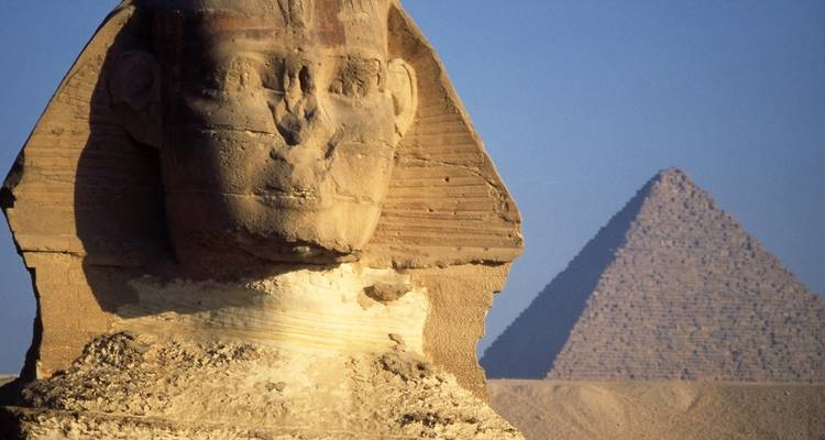Close-up of the Sphinx with the Great Pyramid in the background.
