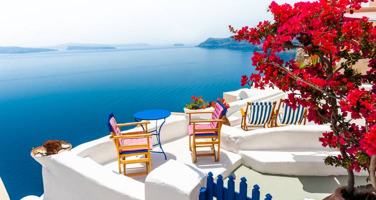 Terrasse de Santorin avec des fleurs colorées et une vue sur la mer.