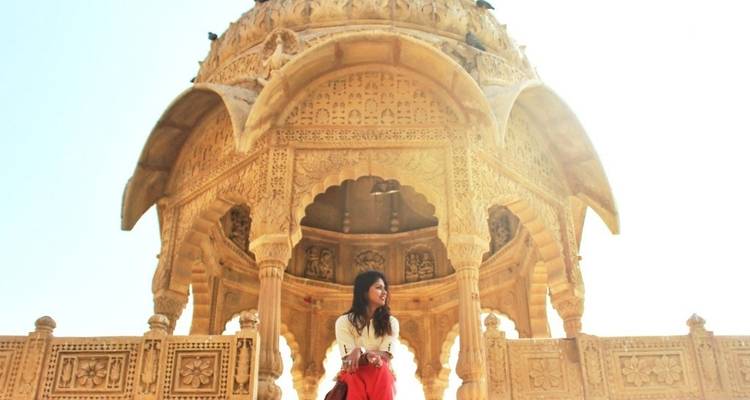 Person seated under an ornate stone pavilion.