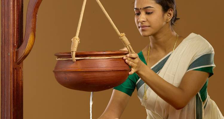 Woman holding a copper pot, possibly involved in traditional practices.