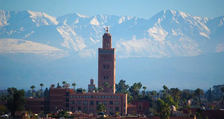 Turm mit schneebedeckten Bergen im Hintergrund.