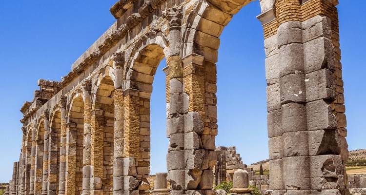 Steinbögen einer antiken Ruine unter einem hellen Himmel.