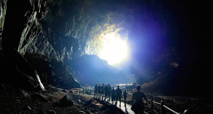 Eine Gruppe von Menschen, die in einer großen Höhle geht, mit einströmendem Licht.