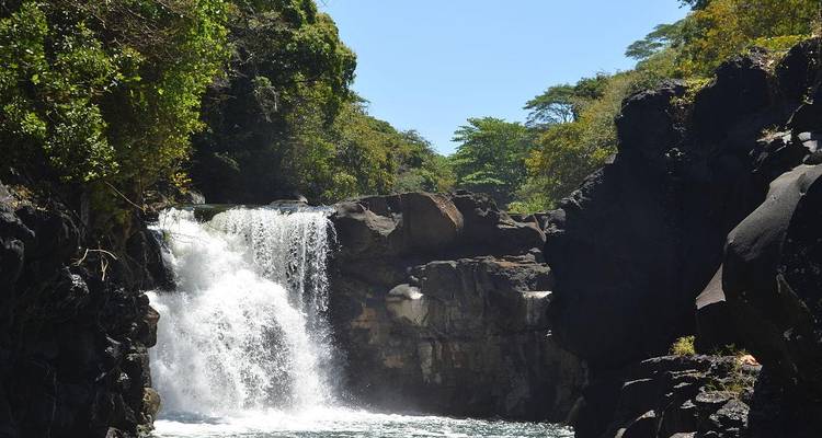 Machtige waterval die tussen donkere vulkanische rotsen naar beneden stort in een schuimend meer