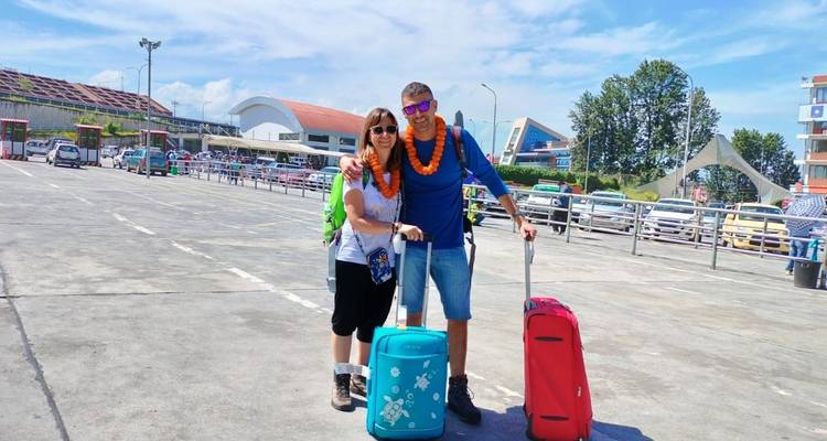 Twee reizigers met bagage op een luchthaven met slingers om hun nek.