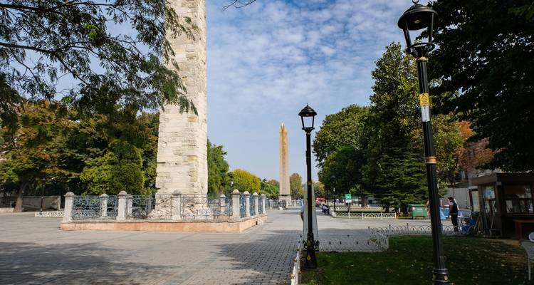 Obélisque et colonne dans une zone semblable à un parc avec des gens qui marchent.