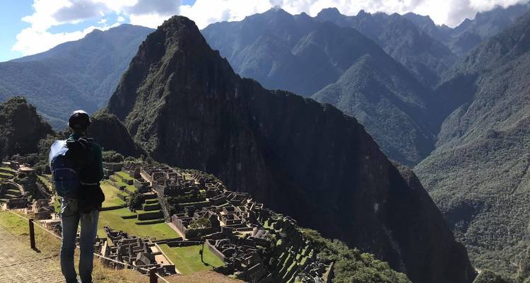 Persoon die uitkijkt over Machu Picchu vanaf een hoog uitkijkpunt.