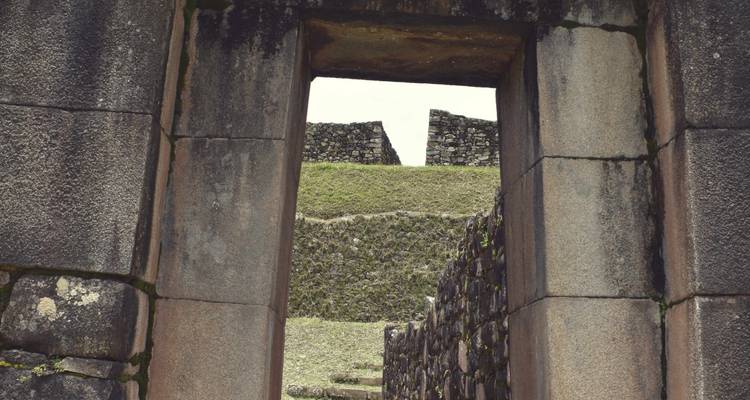 Een stenen deuropening die leidt naar oude stenen bouwwerken.