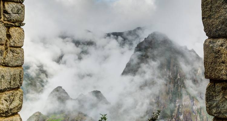 Mistig bergzicht omlijst door oude stenen muren.