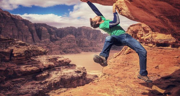 Een persoon die aan het rotsbeklimmen is in een ruig woestijnlandschap.
