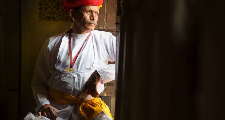 Mann in traditioneller Kleidung, der an einem Fenster bei schwachem Licht sitzt.