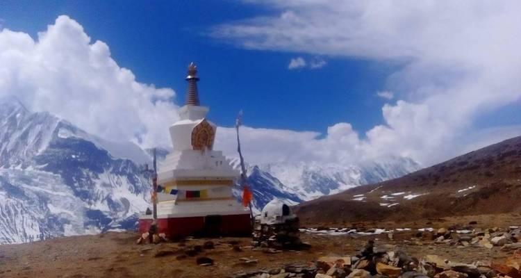 Stupa mit Gebetsfahnen in einer bergigen Landschaft.