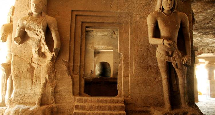 Sculptures en pierre dans une grotte ancienne avec des marches.