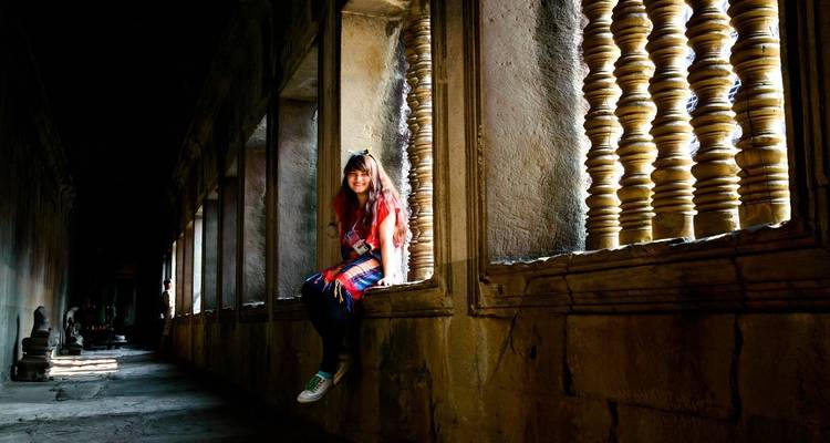 Femme assise dans le couloir d'un temple ancien avec des piliers ornés.