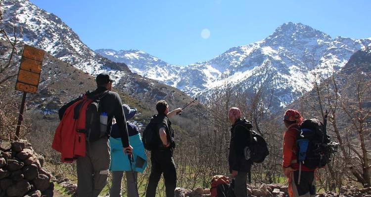 Groep wandelaars wijzend naar besneeuwde bergen.