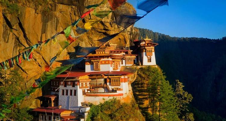 Monastery perched on a cliff with colorful prayer flags.