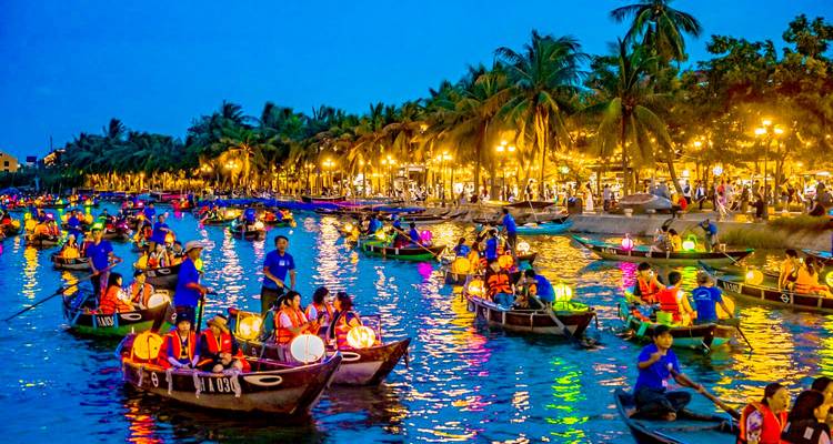 Kleurrijke nachtmarkt op een rivier met boten en lantaarns.