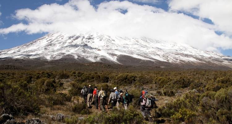 Hikers trekking through a snowy landscape at the summit of a mountain.