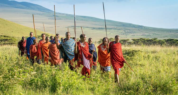 Maasai warriors walking in formation on a grassy plain.