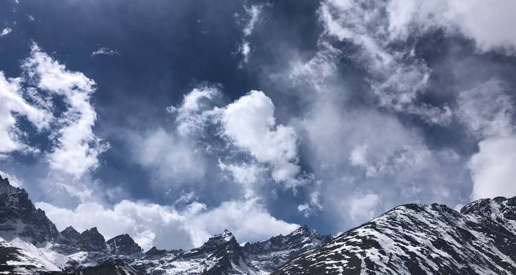 Montagnes enneigées sous des nuages dramatiques.