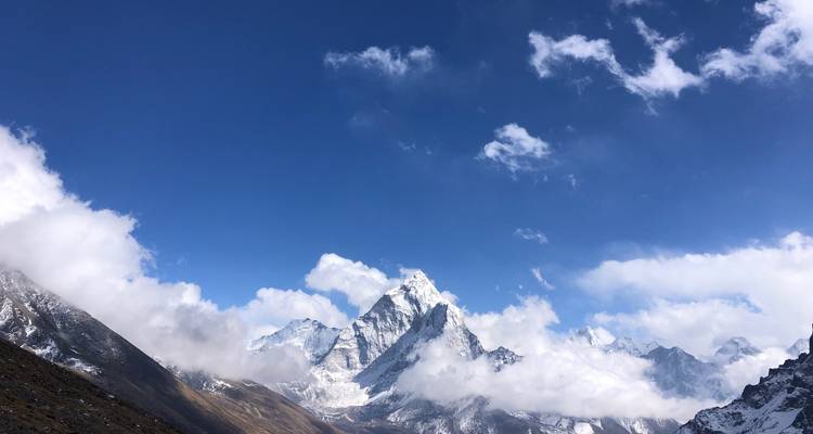 Pic de montagne pointu s'élevant vers le ciel bleu avec des nuages.