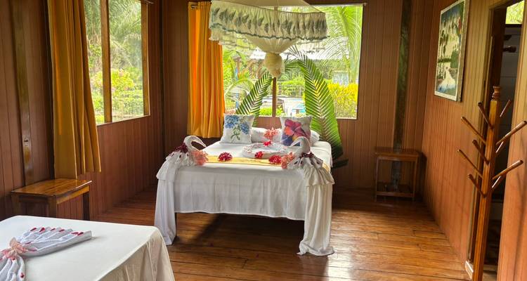Habitación con una cama grande, decorada con toallas y flores, interior de madera.