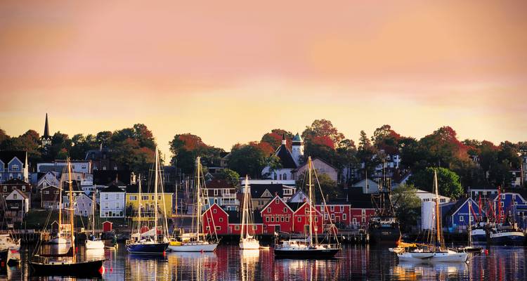 Les maisons historiques aux couleurs vives et les voiliers se reflétant sur un port calme à la tombée de la nuit
