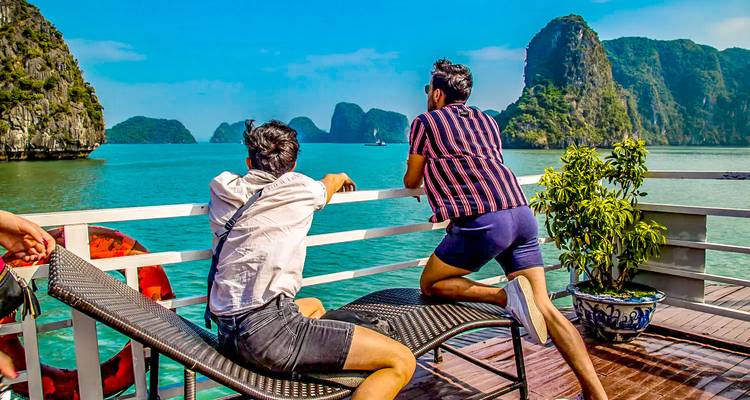 Tourists relaxing on a boat with Halong Bay's scenery.