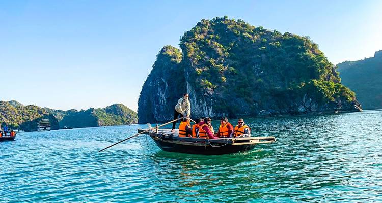 Touristen auf einem Boot in einer malerischen Bucht mit üppigen Hügeln.