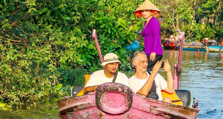 Touristen, die Selfies auf einem Boot in einer üppigen Gegend machen.