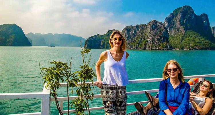 Drei Frauen genießen eine Bootsfahrt mit malerischen Klippen im Hintergrund.
