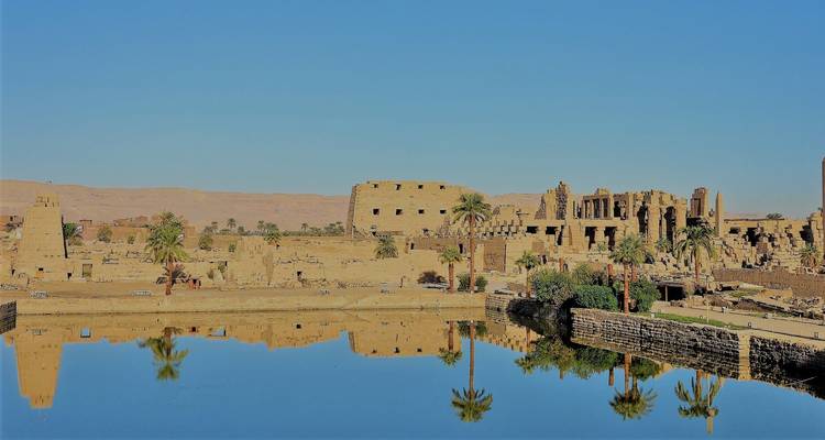 Spiegelungen antiker Ruinen auf dem Wasser bei klarem Himmel.
