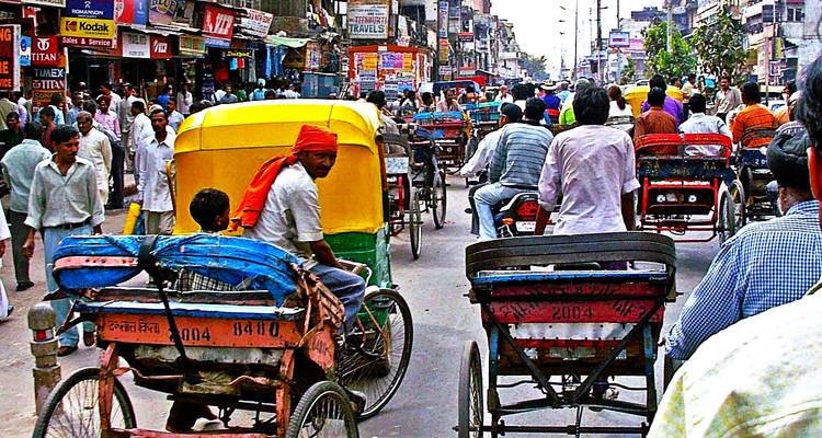 Belebte Straße mit Rikschas und Menschen.