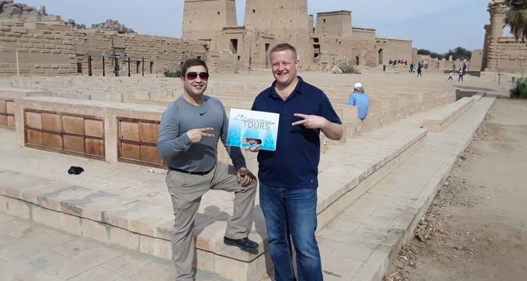 Twee mannen poseren met een bord in oude ruïnes