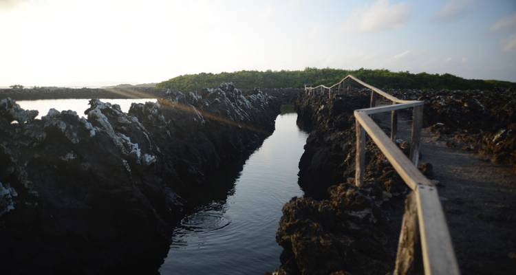 Pathway through jagged rocks bordered by still water.