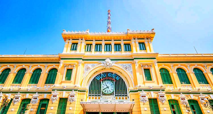 El exterior de un gran edificio de oficina postal con una torre de reloj.