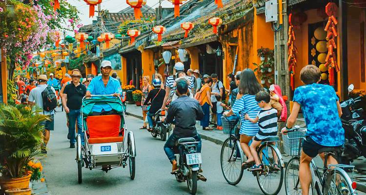 Una calle concurrida con ciclistas y decoraciones vibrantes.
