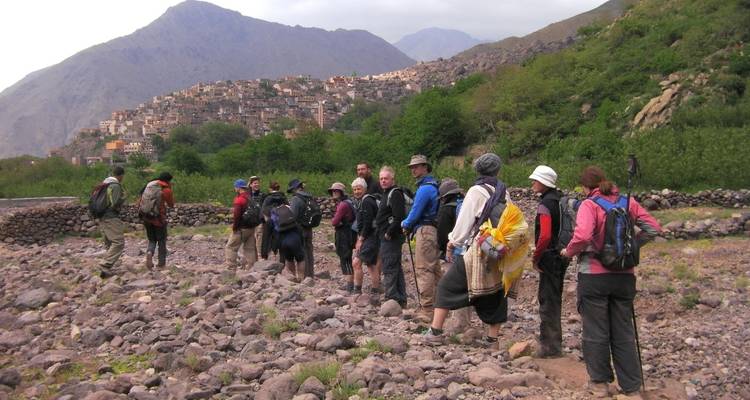 Grupo de excursionistas caminando hacia un pueblo montañoso.