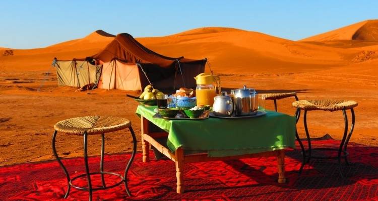 Woestijnkampeerplaats met ontbijt op tafel gezet.